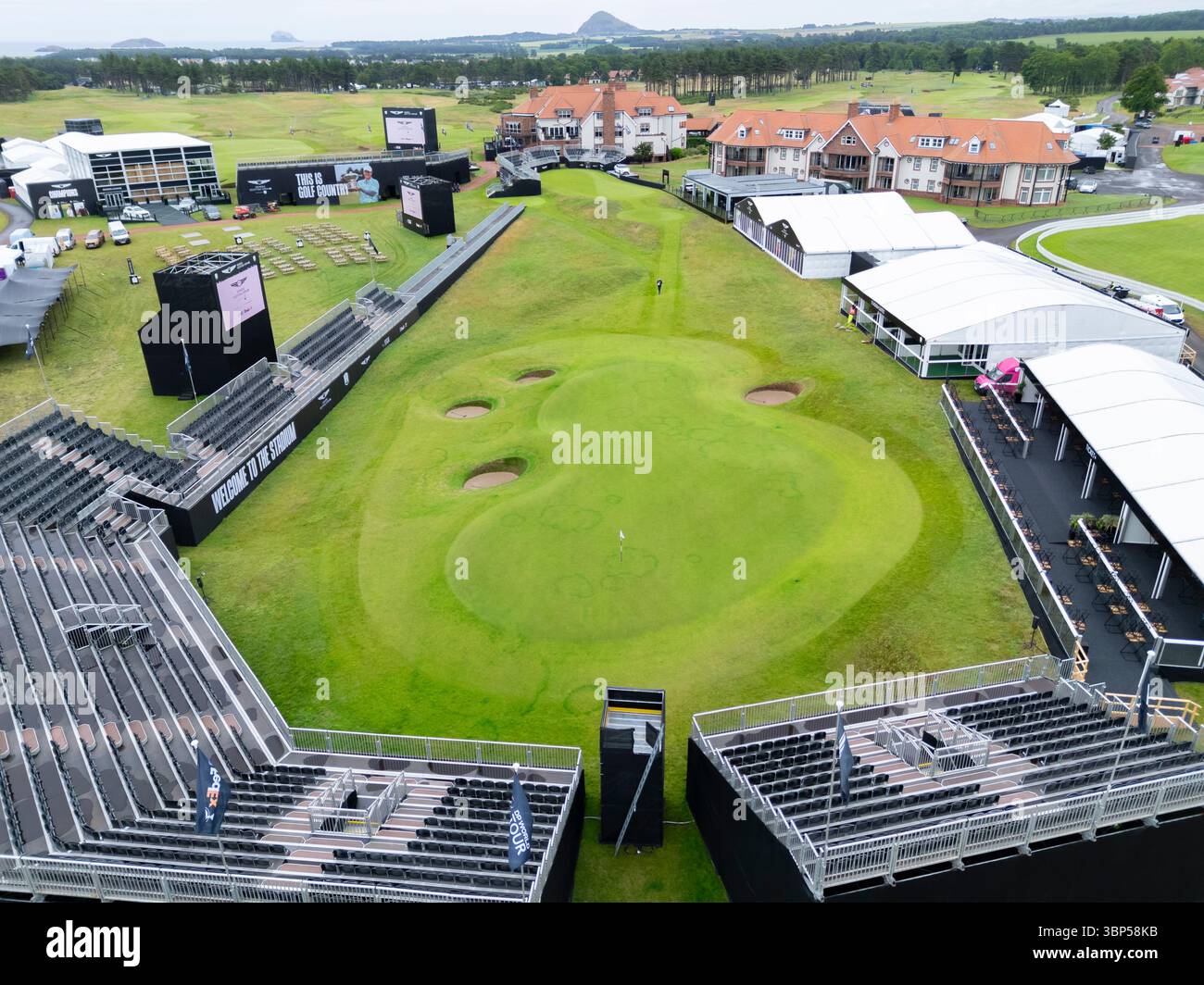 Gullane, East Lothian, Scozia, Regno Unito. 6 luglio 2025. Visualizza in anteprima le immagini del Renaissance Club vicino a Gullane, che questa settimana ospita il campionato di golf Genesis Scottish Open. L'evento è diventato un appuntamento importante nell'anno del golf e ha attirato 8 dei 10 migliori giocatori del mondo nella settimana precedente l'Open . PIC; veduta aerea del par 3 6th Green, circondato da tribune per gli spettatori in una disposizione di buche dello stadio. Iain Masterton/Alamy Live News Foto Stock