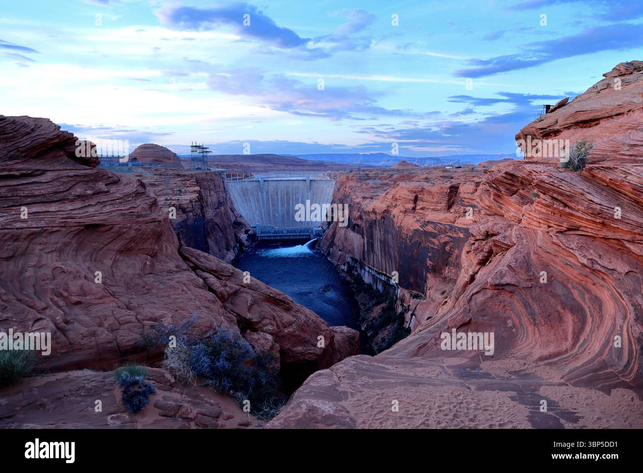 La diga di Glen Canyon sorge sopra il deserto dell'Arizona incorniciata da vorticose arenarie rosse e cielo blu, una vera unione della bellezza della natura e del potere ingegneristico umano Foto Stock