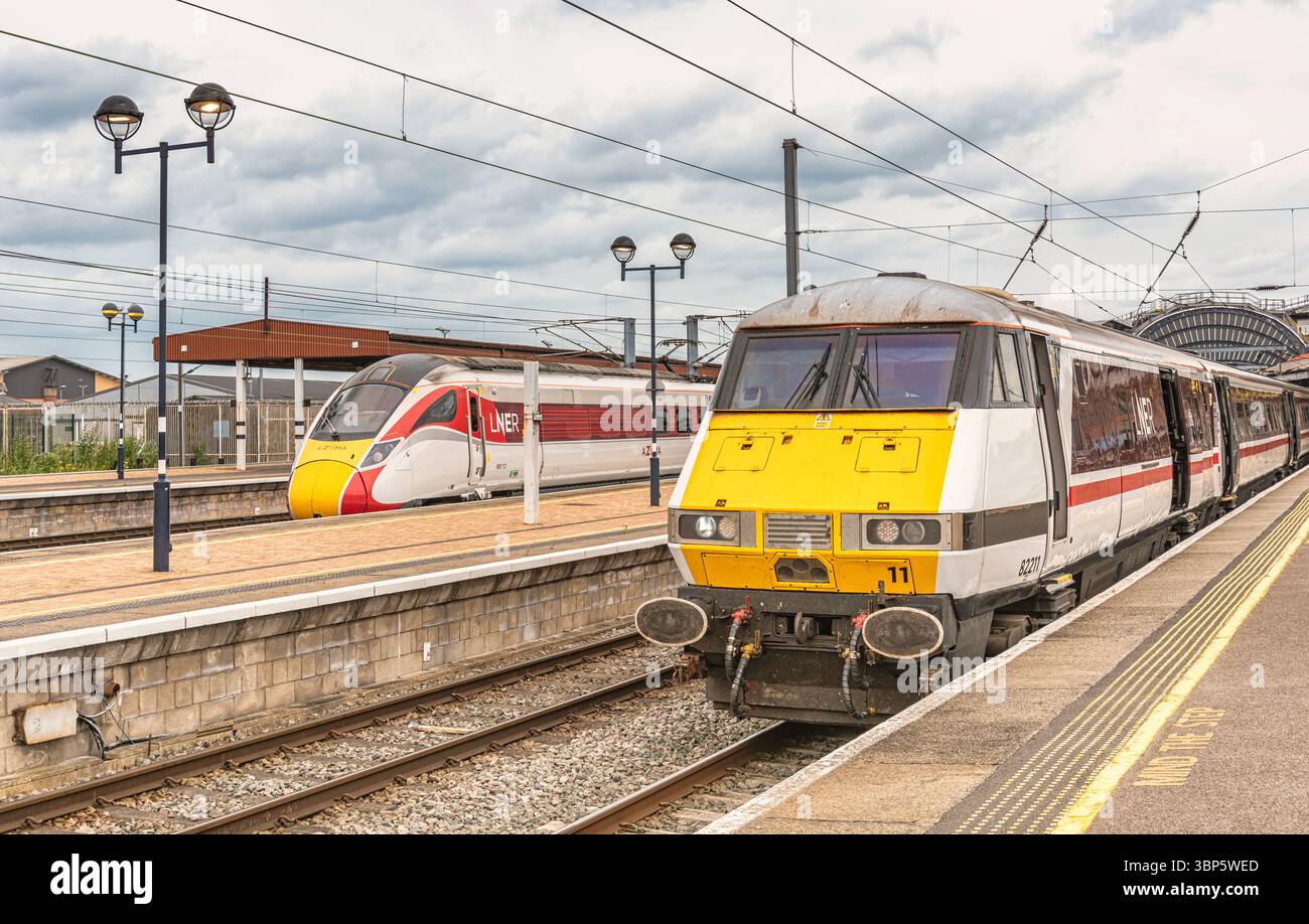 Un treno Intercity 225 con una locomotiva elettrica di Classe 1 si trova accanto ad una piattaforma storica del XIX secolo. Dietro c'è un moderno treno Azuma e un'arguzia del cielo Foto Stock