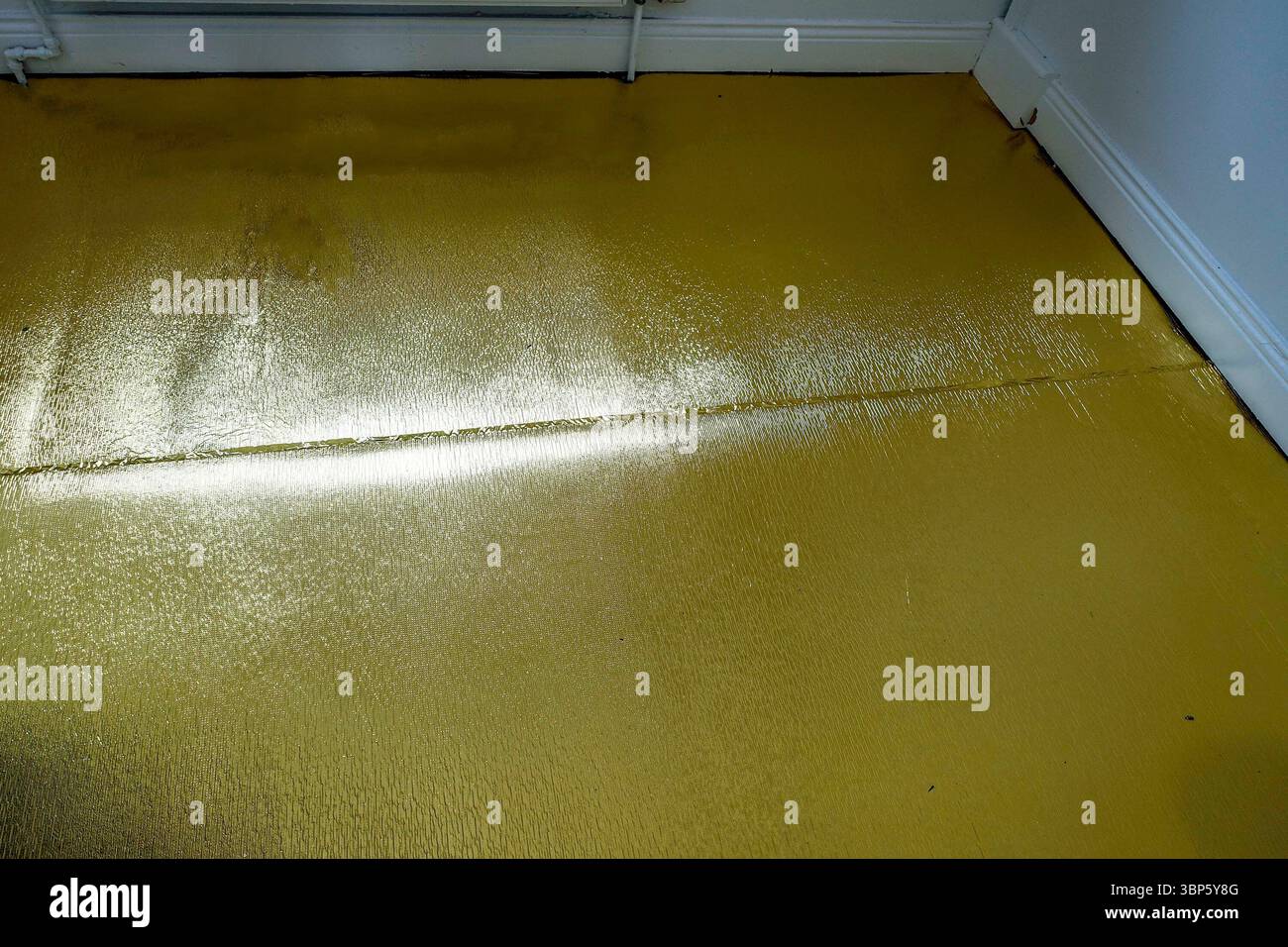 Sottocopertura acustica in oro installata per pavimenti in laminato, che fornisce isolamento acustico e protezione dall'umidità durante la ristrutturazione della casa. Foto Stock