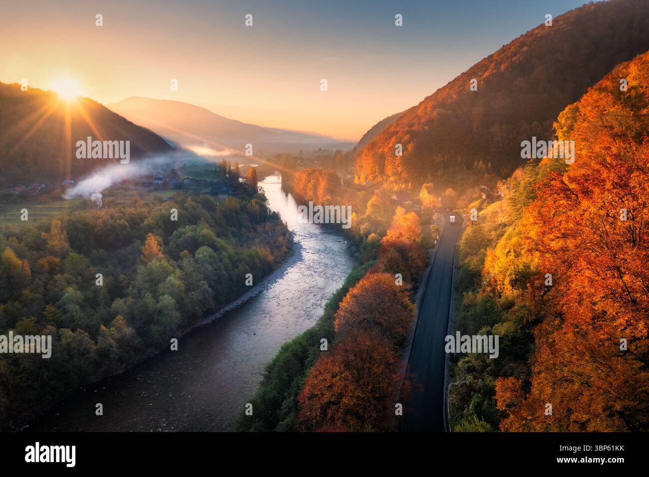 Vista aerea di un fiume tortuoso, di una strada e di una vibrante foresta autunnale Foto Stock