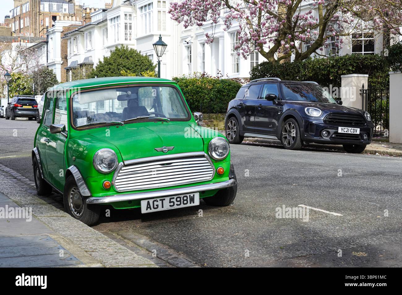 Vecchia auto d'epoca Morris Mini Cooper a due porte parcheggiata accanto alla nuova versione moderna a quattro porte in una strada residenziale a Londra, Inghilterra, Regno Unito Foto Stock