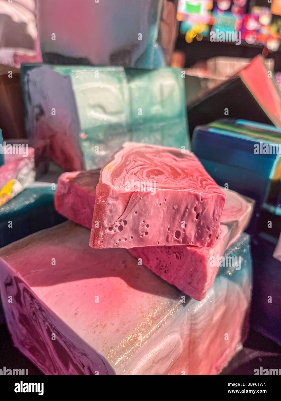 Le colorate saponette fatte a mano sono impilate in modo creativo, evidenziando le loro texture e i loro motivi unici, promuovendo la sostenibilità e gli ingredienti naturali Foto Stock