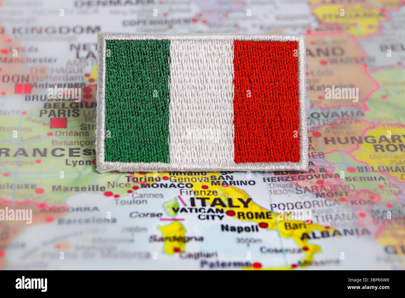 Bandiera della Repubblica Italiana ricamata su tessuto, ambientata su Roma sulla mappa del mondo. Segno di orgoglio nazionale e di viaggi culturali. Foto Stock