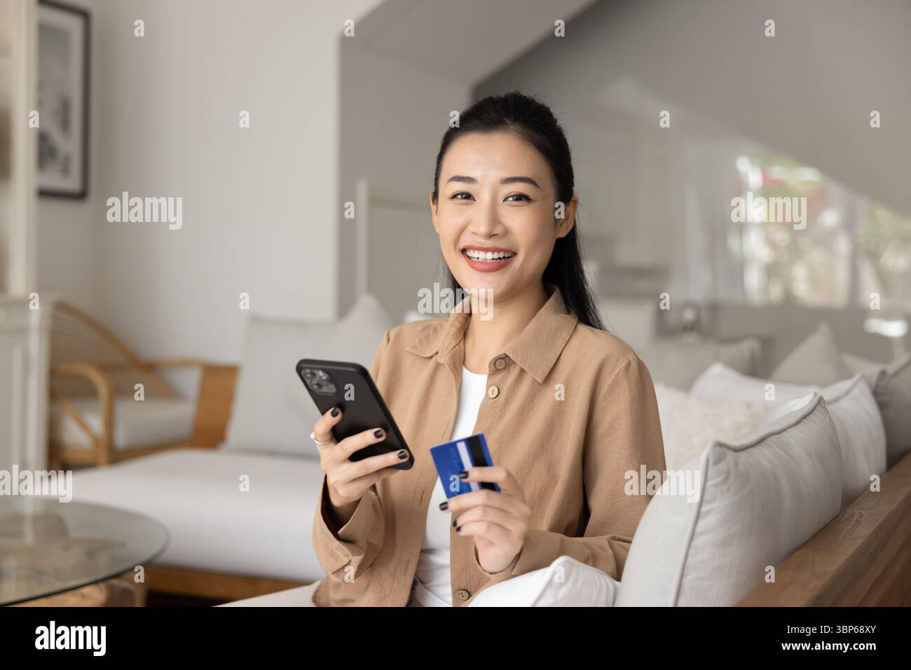 Ritratto di donna che guarda la fotocamera che tiene la scheda e lo smartphone Foto Stock