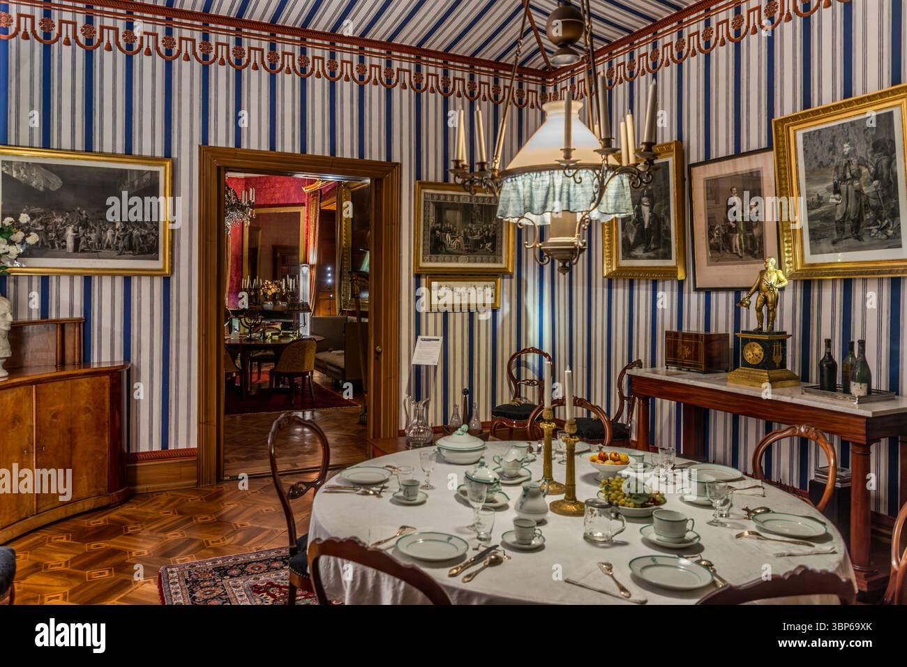 Qui è raffigurata una storica sala da pranzo o salotto nel castello di Arenenberg a Salenstein, in Thurgau, in Svizzera. La camera, caratterizzata dalla sua carta da parati a righe, mobili antichi e quadri incorniciati, mostra un tavolo posato con raffinati piatti. Dà un'idea dello stile di vita degli ex residenti, come Hortense de Beauharnais e suo figlio Luigi Napoleone Foto Stock