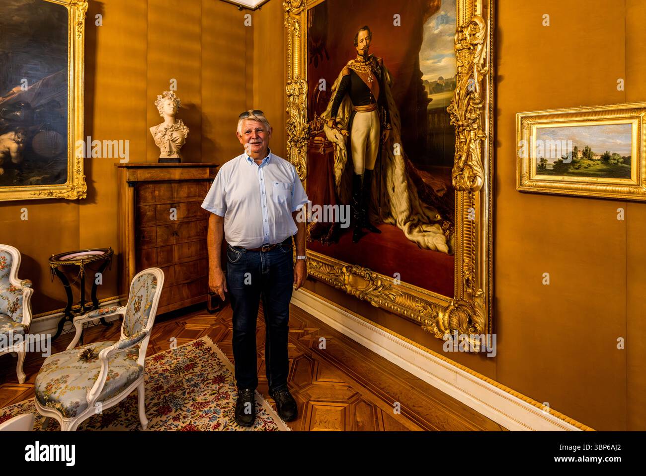 Il direttore del museo Dominik Gügel si trova al Museo Napoleone Arenenberg accanto a un dipinto ritrattistico che raffigura Napoleone III in uniforme, con un mantello di ermellino. Arenenberg, Salenstein, Turgovia, Svizzera. Foto Stock