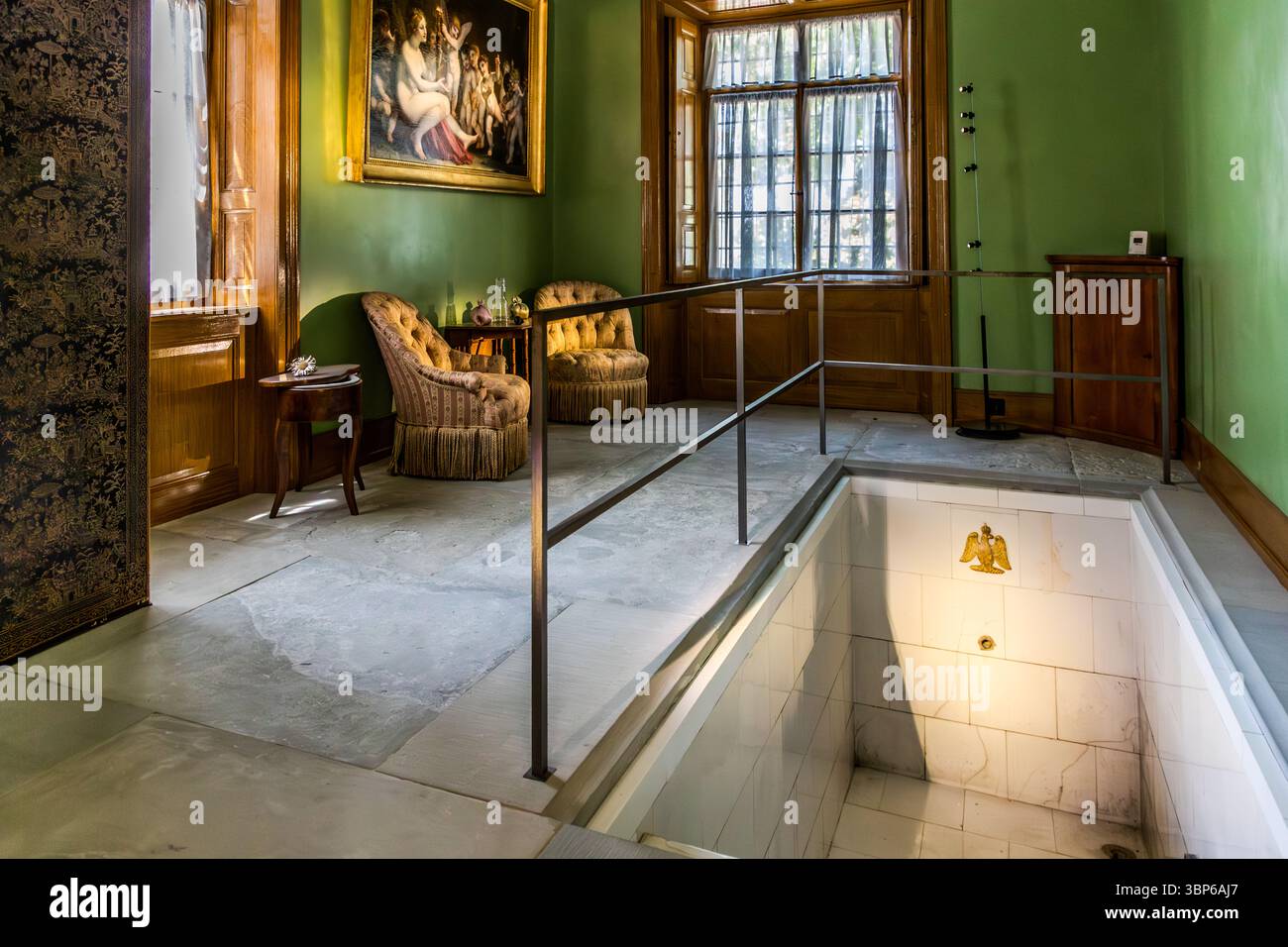 Il bagno storico nel castello di Arenenberg a Salenstein, Thurgau, Svizzera. La camera dispone di un bagno romano incassato con un emblema di aquila napoleonica, circondato da mobili eleganti e da un dipinto classico. Questa area privata era un tempo utilizzata da Hortense de Beauharnais, regina d'Olanda e madre di Napoleone III, e riflette lo stile di vita lussuoso dell'epoca Foto Stock