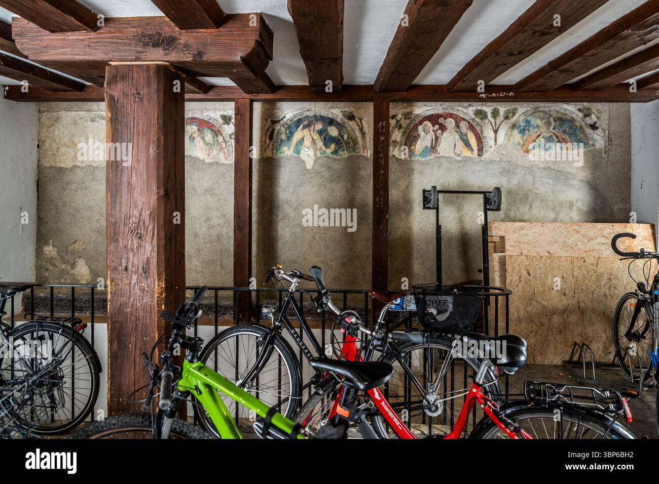 La parete di una sala storica adibita a parcheggio per biciclette presenta affreschi. Travi in legno sostengono il soffitto. Münsterplatz, Costanza, Baden-Württemberg, Germania Foto Stock