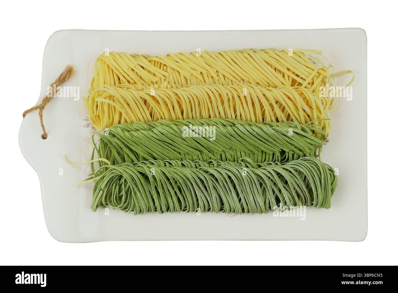 Tipi di pasta cruda. Modello gastronomico. Vista dall'alto. Tagliatelle di uova e spinaci su un pannello di ceramica isolato su sfondo bianco. Foto Stock