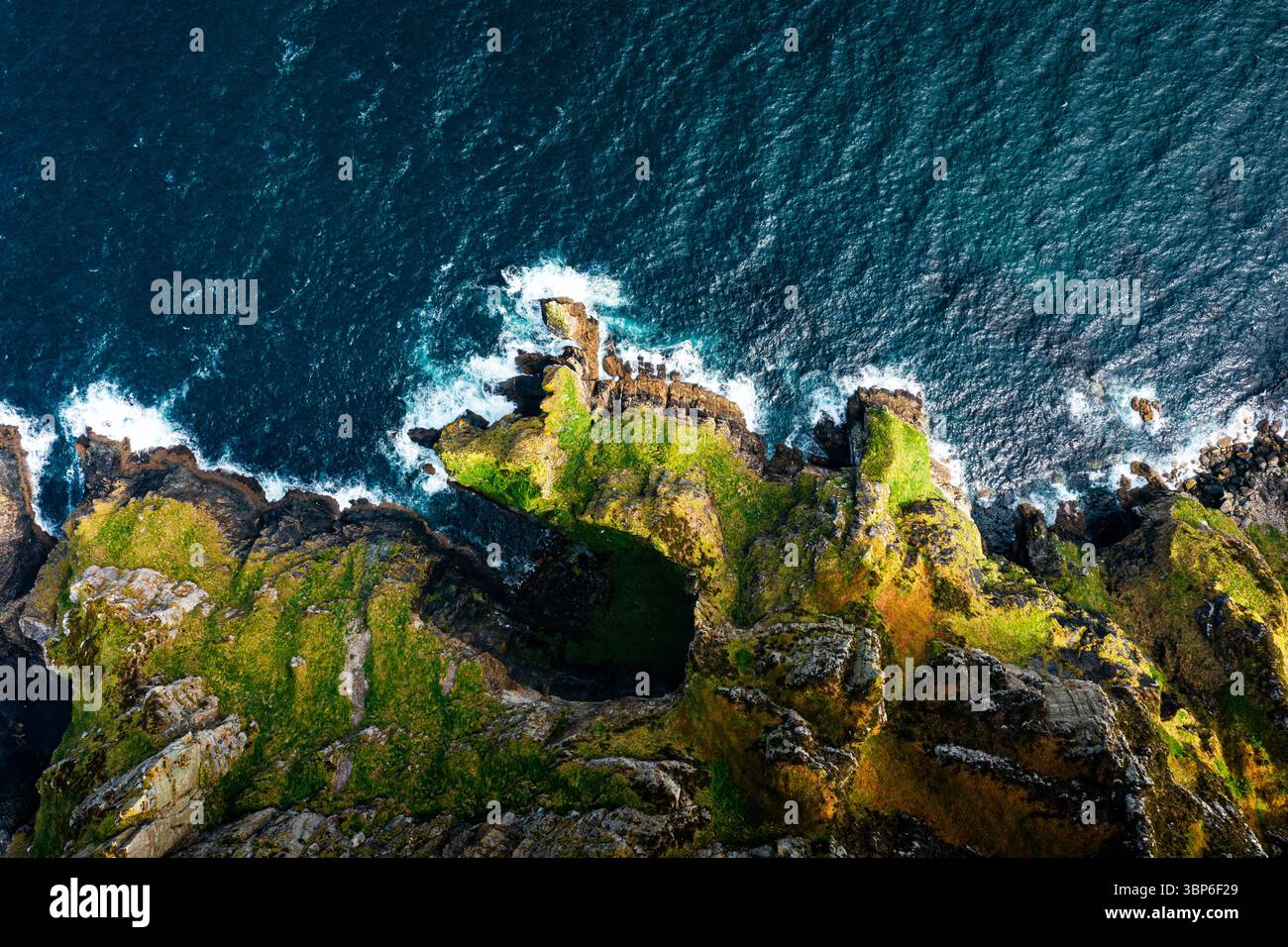 Vista dall'alto verso il basso delle scogliere di Horn Head con uccelli marini e onde dell'Atlantico spumeggianti durante una giornata di sole Foto Stock