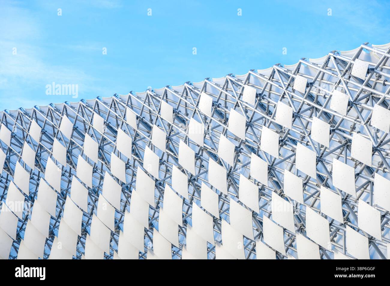 La struttura presenta una facciata geometrica unica fatta di elementi in vetro e metallo, che riflette il cielo azzurro Foto Stock