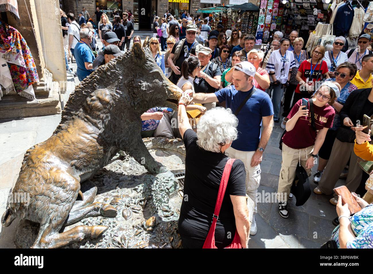 Firenze, Italia - 10 maggio 2025: I turisti si riuniscono intorno alla statua del Porcellino, prendendo parte alla tradizione di toccare il muso di cinghiale per buona fortuna Foto Stock
