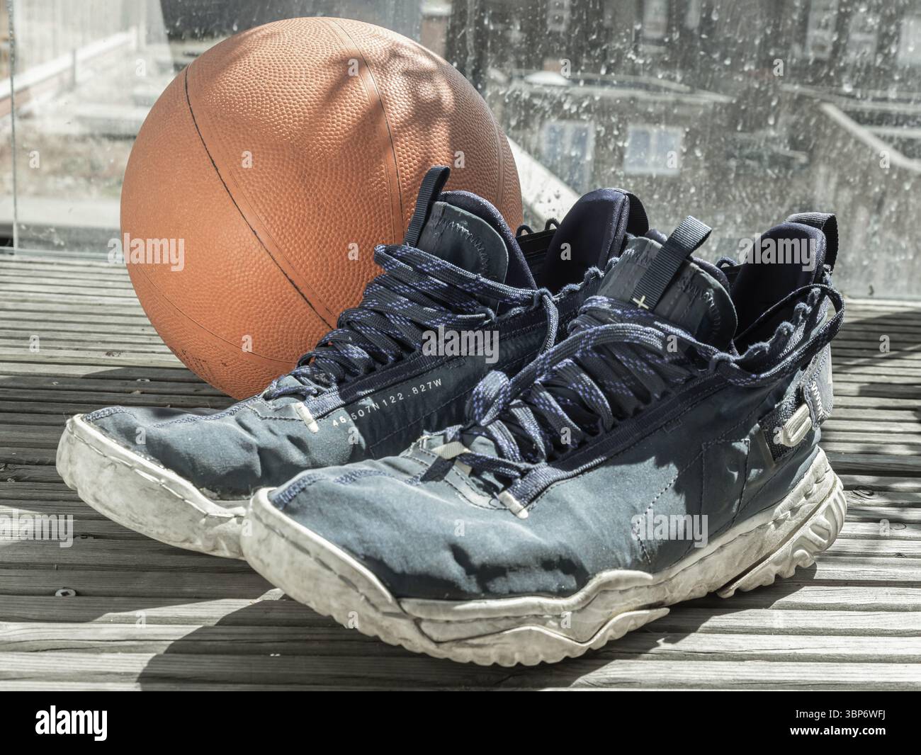 Londra, Regno Unito - 17 maggio 2025 - scarpe da pallacanestro e palla da basket vengono posizionate sul balcone, dopo l'allenamento da basket. Usala come Wal Foto Stock