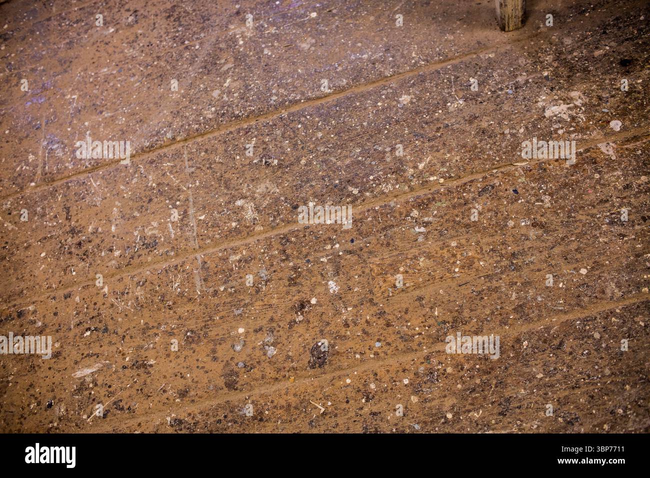 Il pavimento in legno usurato mostra spruzzi di vernice, polvere, detriti con palo in legno nella scena piatta dell'officina Foto Stock