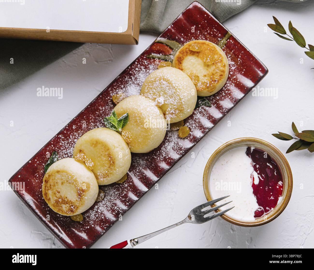 Cibo, vista dall'alto dei pancake gourmet con zucchero a velo, accompagnati da salsa e decorazioni verdi Foto Stock