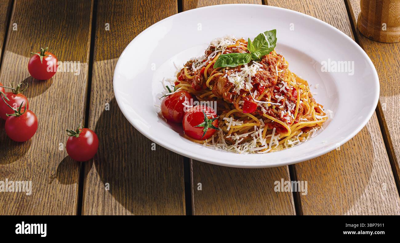 Cibo e pasta presentati splendidamente su un caldo tavolo di legno, evocando un'atmosfera intima da pranzo italiana Foto Stock