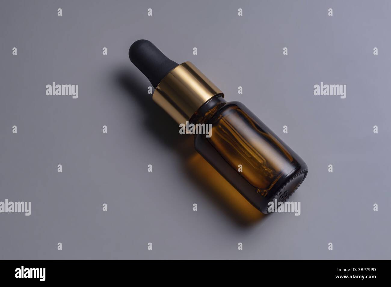 Flacone contagocce cosmetico in vetro ambrato con etichetta vuota su sfondo grigio. Design e branding di prodotti di bellezza alla moda. Cosmetici da mockup Foto Stock