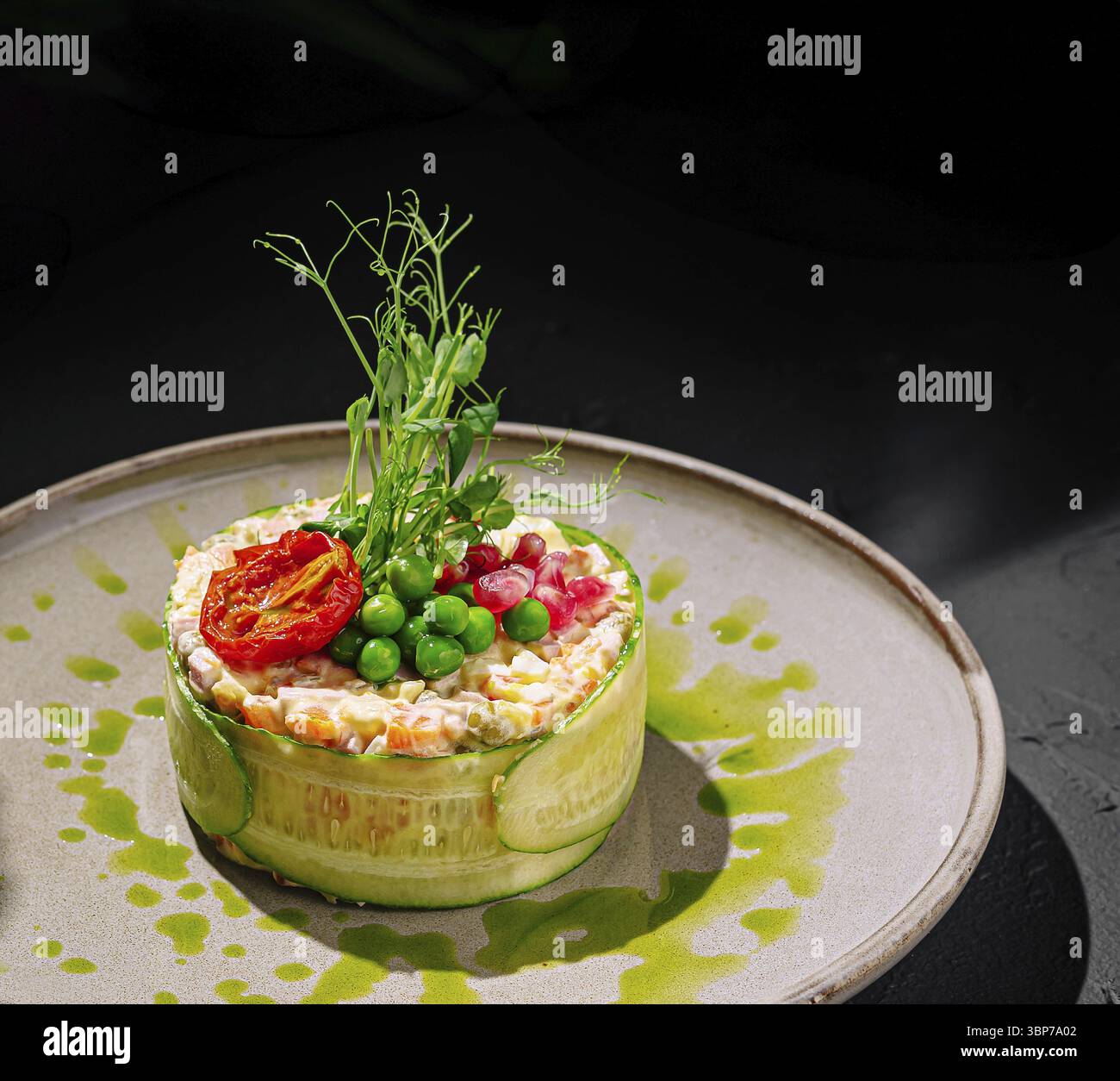 Il cibo, Un'insalata colorata e artistica, con verdure fresche e verdi, è splendidamente placcato. Ingredienti vivaci come piselli e pomodori secchi al sole Foto Stock