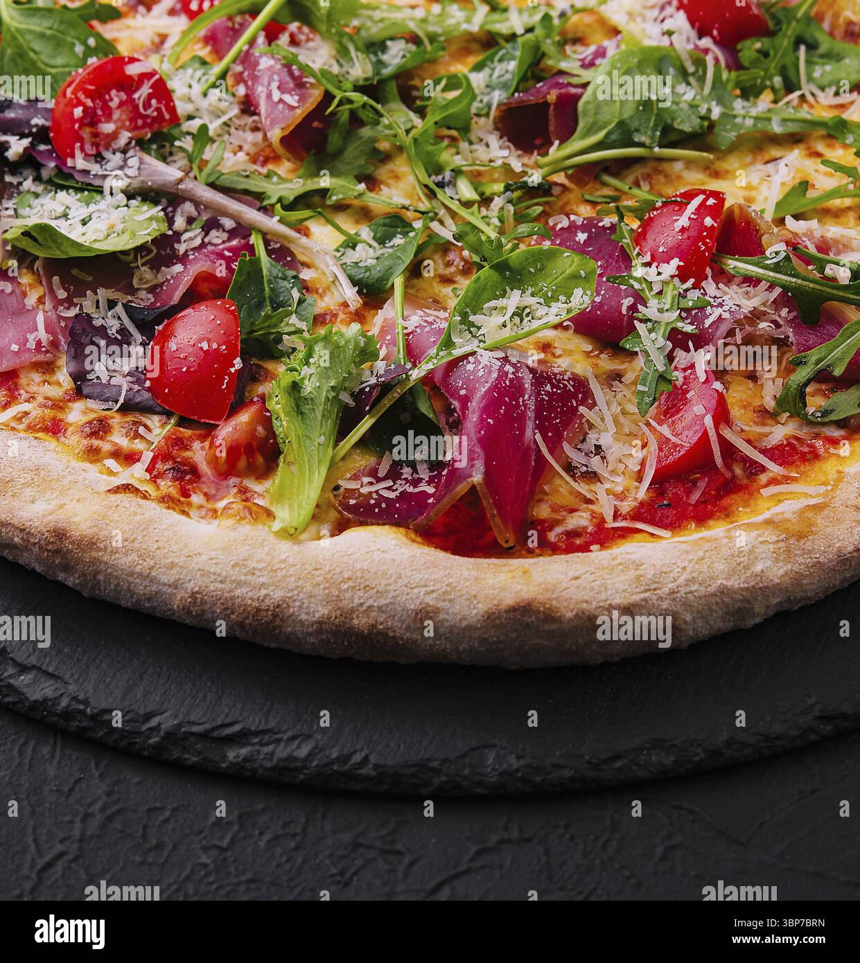 Cibo, pizza italiana con prosciutto, rucola e pomodori ciliegini Foto Stock