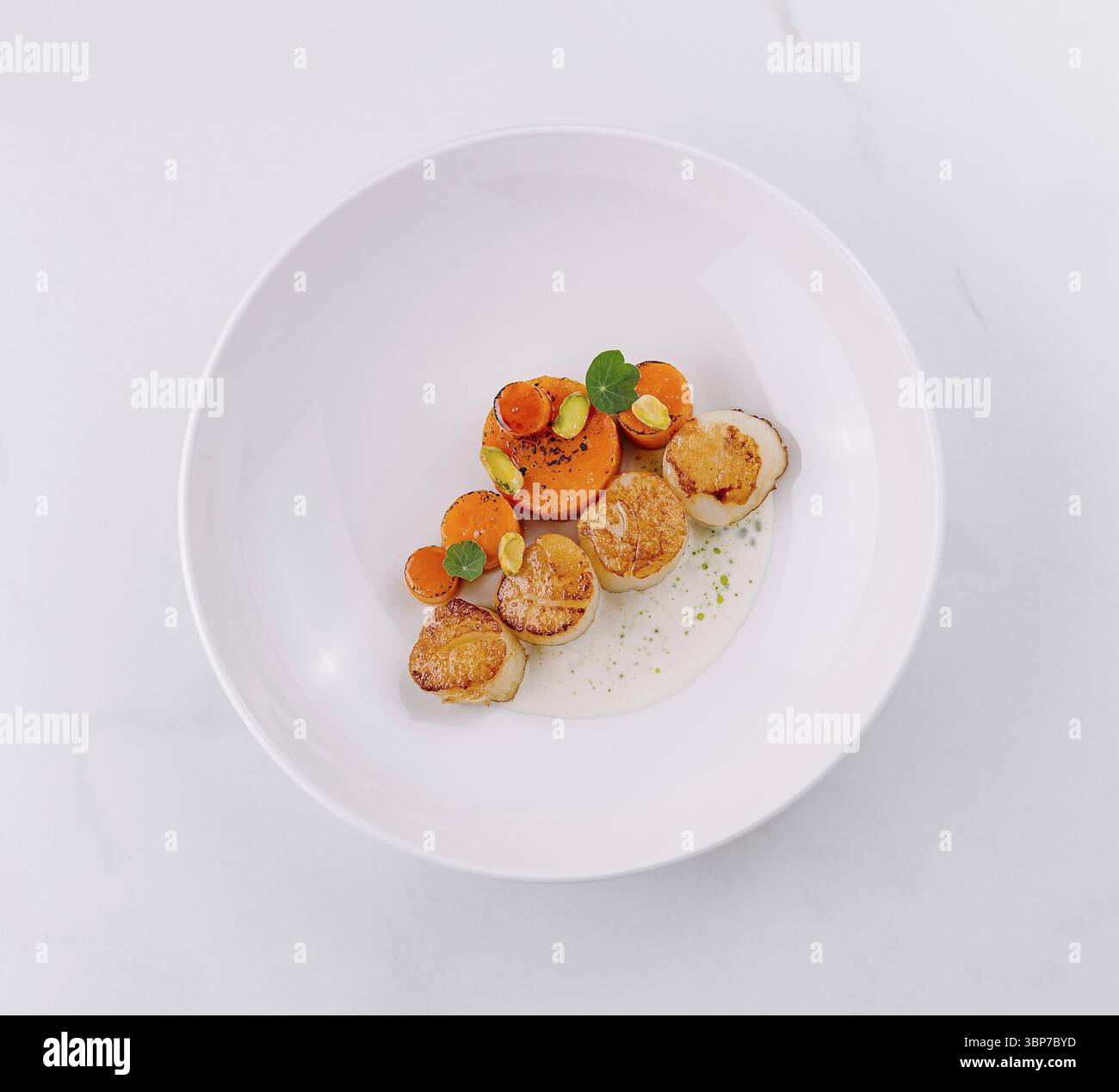 Ristorazione, Teller mit gebratenen Jakobsmuscheln, garniert mit Karotten und Pistazien, servizio nel ristorante einem Foto Stock