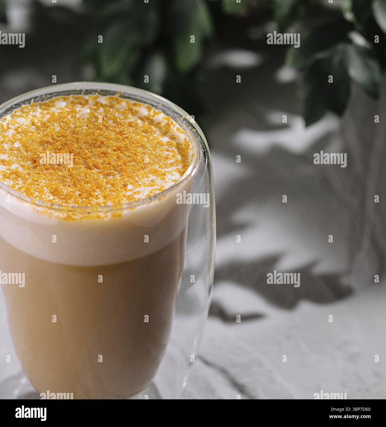 Cibo, sano latte dorato di curcuma in un contemporaneo vetro trasparente, presentato su una superficie bianca testurizzata Foto Stock