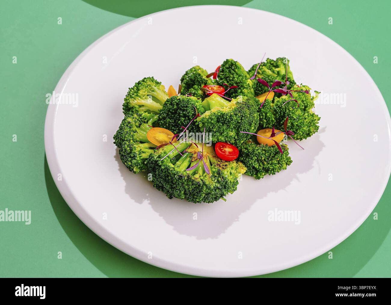 Cibo, florets di broccoli al vapore con pomodori e microverdure che compongono un piatto sano su un piatto bianco Foto Stock