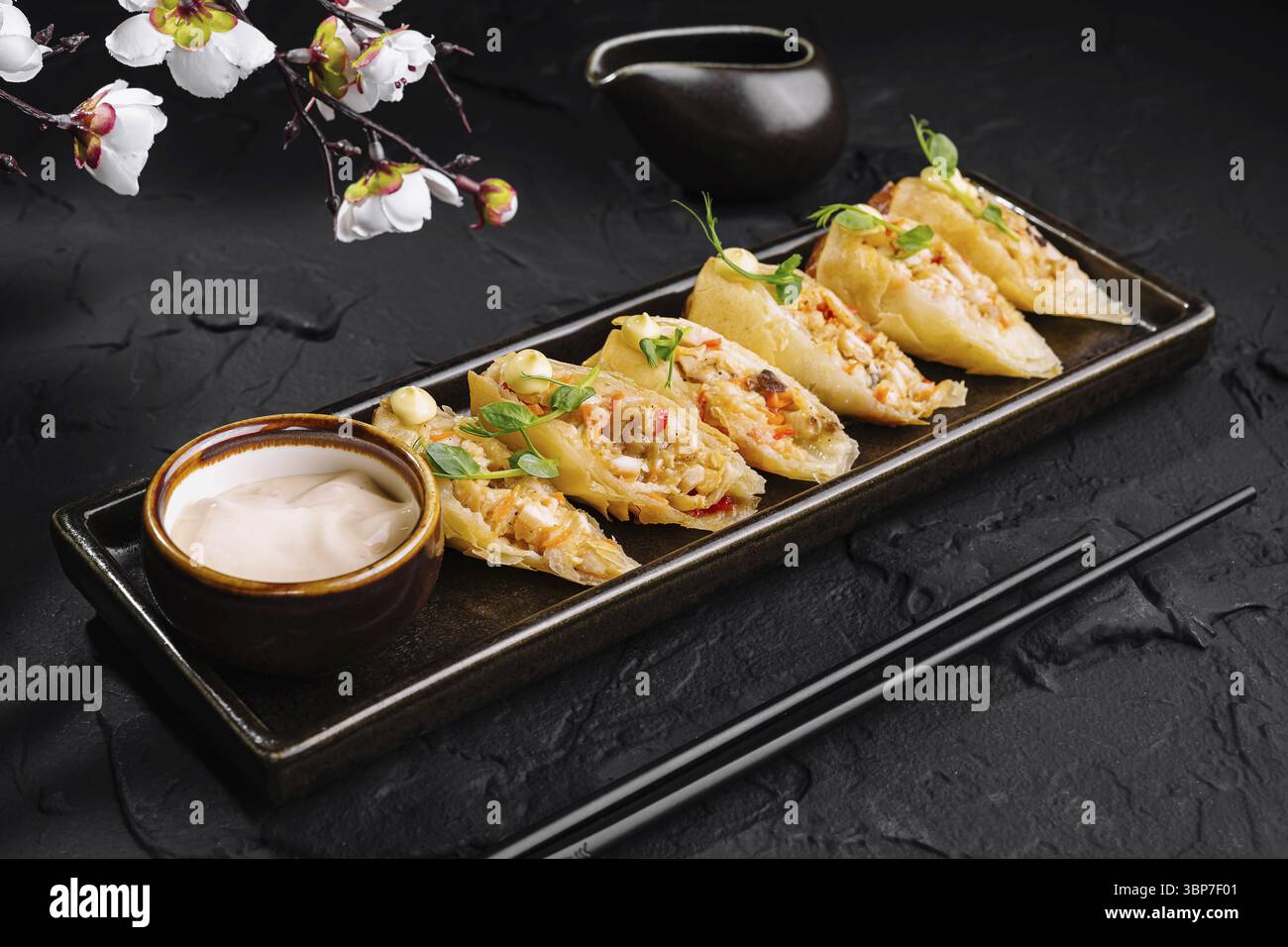 Cibo, piatto di deliziosi gnocchi al vapore serviti con salsa accanto a un ramo fiorito Foto Stock