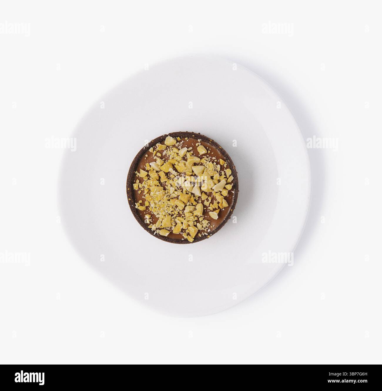 Cibo, vista dall'alto di una crostata di cioccolato ricoperta di noci schiacciate su un piatto bianco pulito Foto Stock