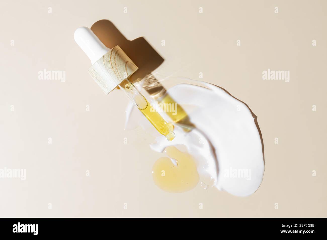 Olio giallo per il viso di bellezza che gocciola dal contagocce di bambù su sfondo beige. Pubblicità cosmetica per la cura della pelle con spazio per copie Foto Stock