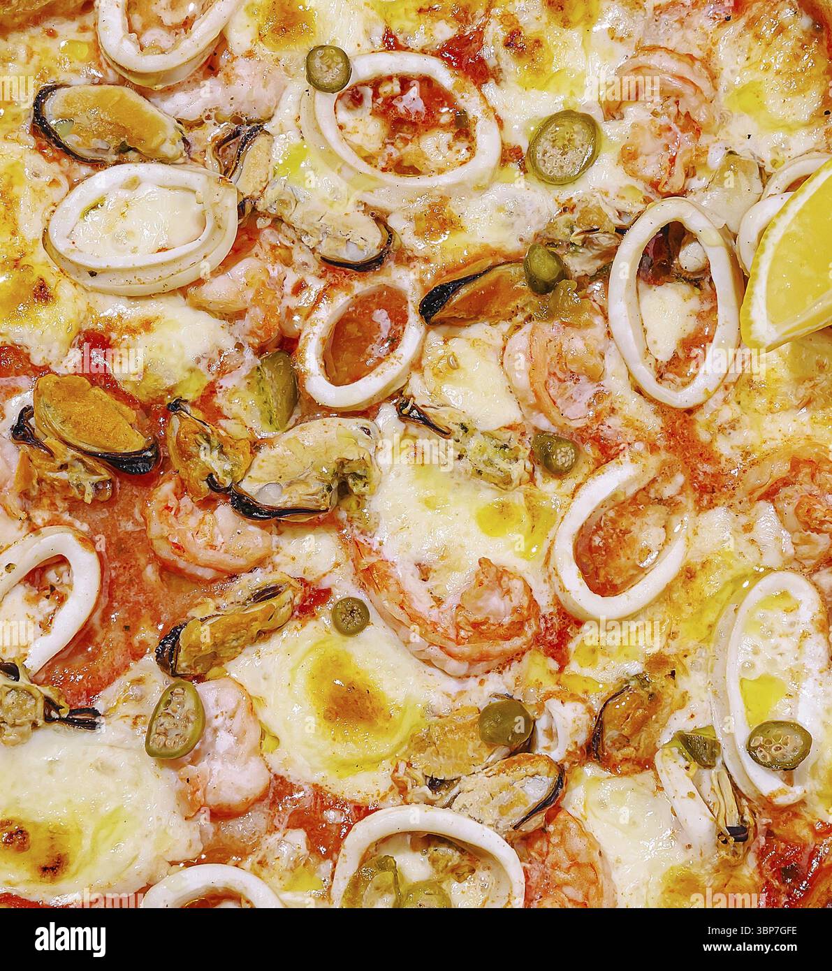 Cibo, Una pizza a base di pesce caldo e' piena di gamberi, calamari, cozze e limone a fette. Il formaggio fuso e una ricca salsa di pomodoro esaltano il delizioso Foto Stock