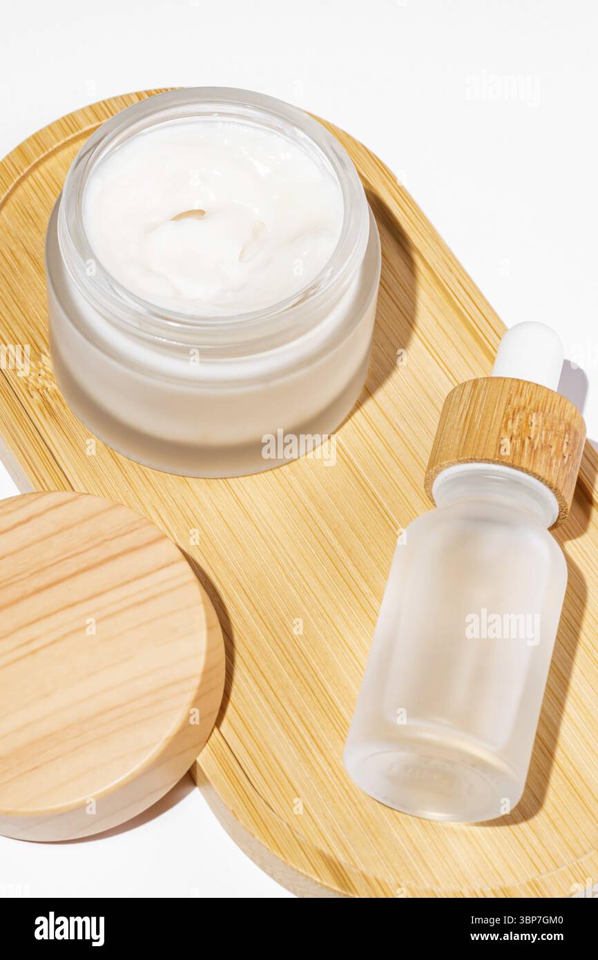 Vaso di panna di bambù e flacone contagocce con olio per il viso su sfondo bianco. Modelli di contenitori cosmetici. Sfondo per la presentazione del branding e del packaging. Foto Stock