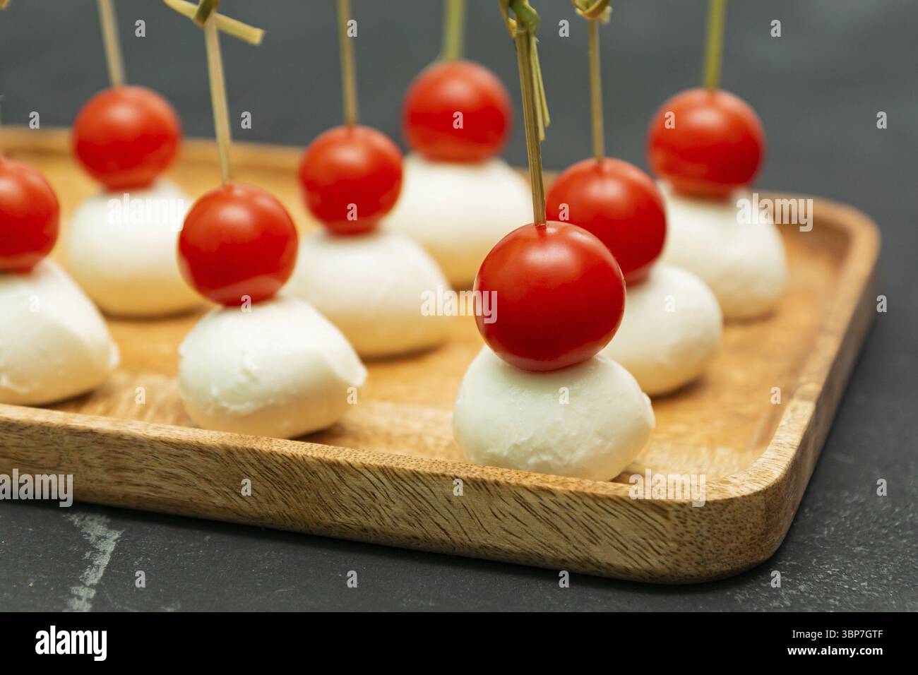 Stuzzichini e antipasti a buffet. Tartine con mozzarella e pomodori ciliegini serviti su vassoio di legno Foto Stock