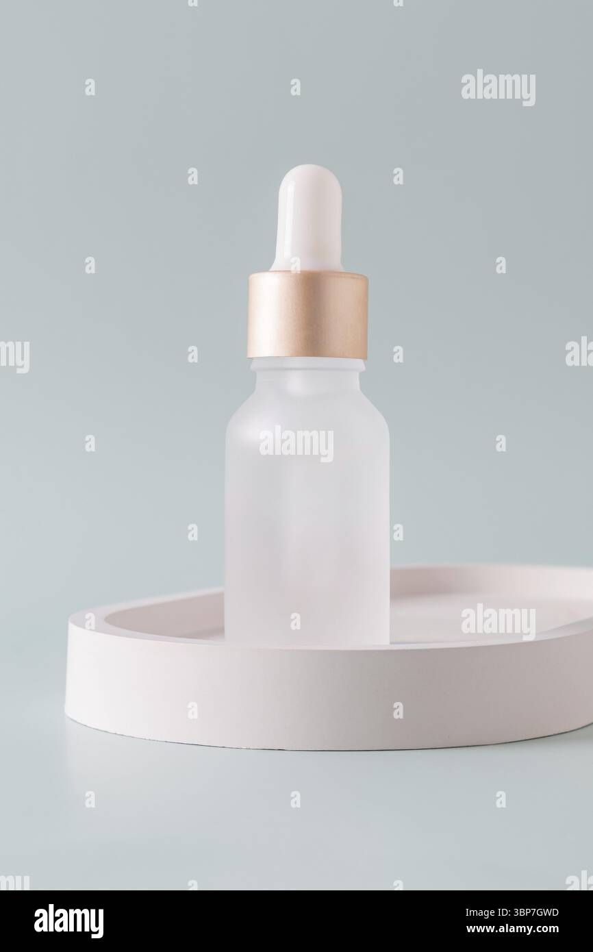 Flacone in vetro smerigliato con pipetta contagocce con siero o olio essenziale su vassoio in cemento Prodotti per la cura della pelle, cosmetici naturali. Concetto di bellezza per Face A. Foto Stock