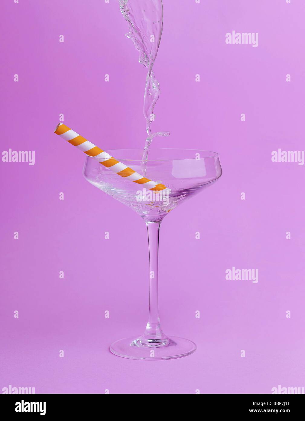 Cibo, vetro martini trasparente con cannuccia di carta arancione e bianca riempita d'acqua su sfondo rosa Foto Stock