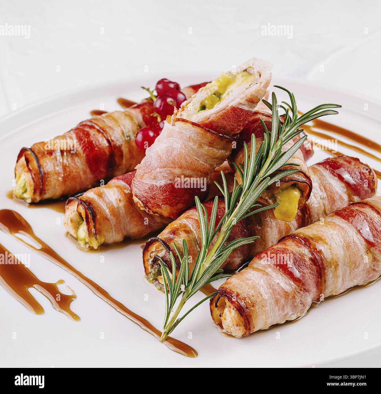 Cibo, jalapenos Gourmet con pancetta ripieno di formaggio, guarnito con rosmarino su un piatto bianco Foto Stock