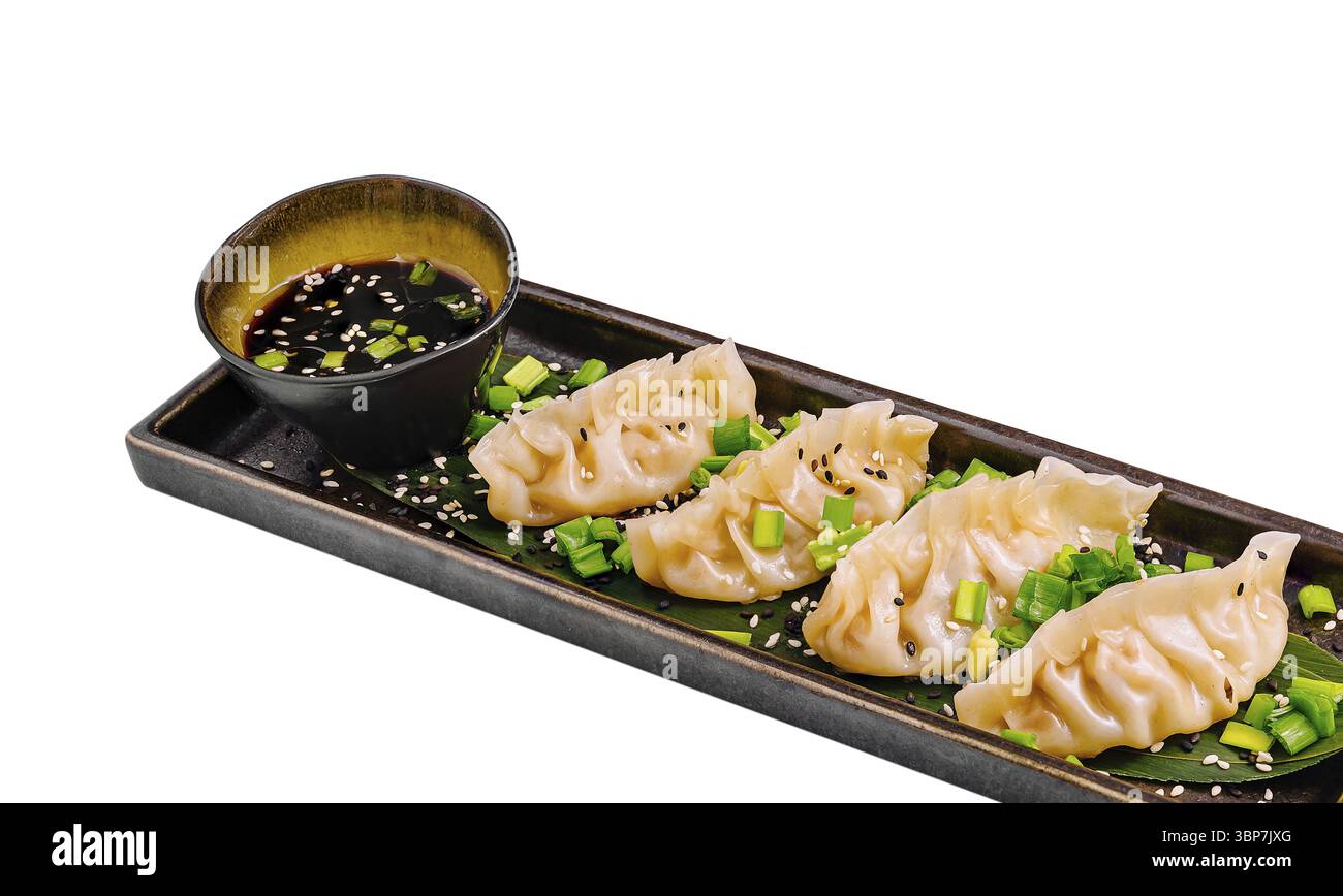 Cibo, cinque gnocchi gustosi sono disposti ordinatamente su un piatto nero rettangolare accanto a una piccola ciotola di salsa salata. Il piatto è guarnito con Foto Stock