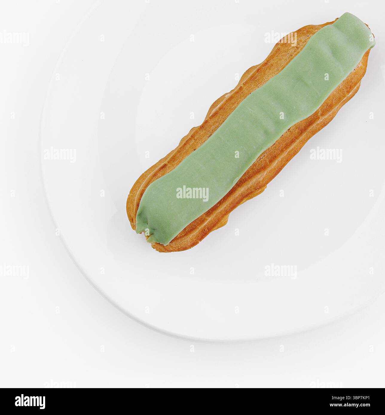Cibo, vista dall'alto di una deliziosa eclair con glassa verde su un piatto bianco pulito, isolato su uno sfondo bianco Foto Stock