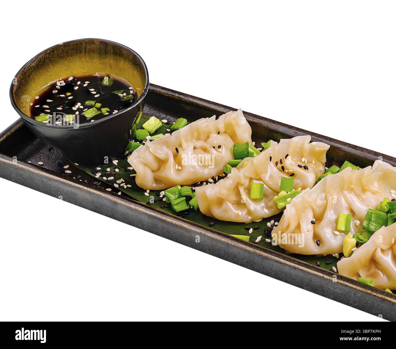 Cibo, Un piatto è composto da gnocchi cotti al vapore guarniti con cipolle verdi tritate e semi di sesamo. Una piccola ciotola contiene una salsa salata, per migliorare la qualità del prodotto Foto Stock