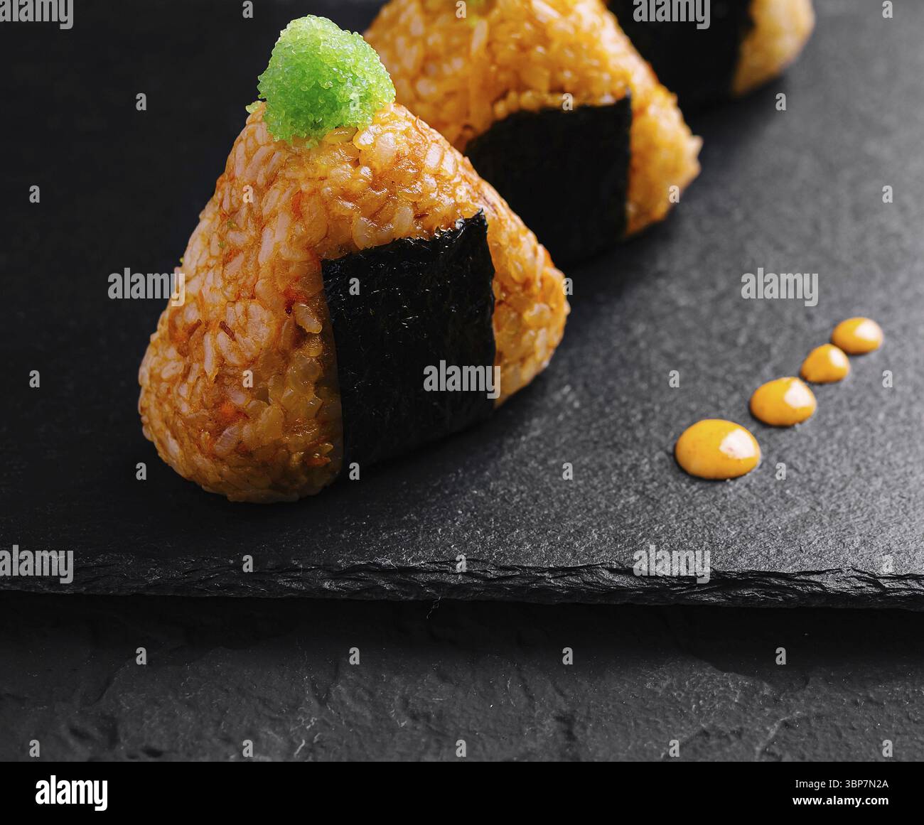 Cibo, pezzi di sushi con una vivace decorazione verde presentati ad arte su una superficie di ardesia nera Foto Stock