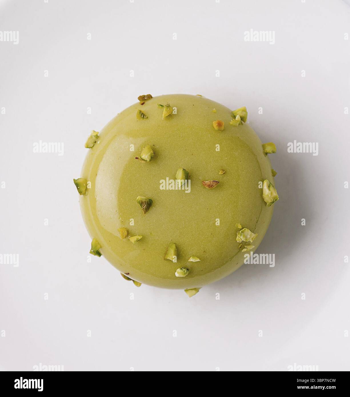 Cibo, macaron singolo al pistacchio decorato con noci isolate su sfondo bianco Foto Stock