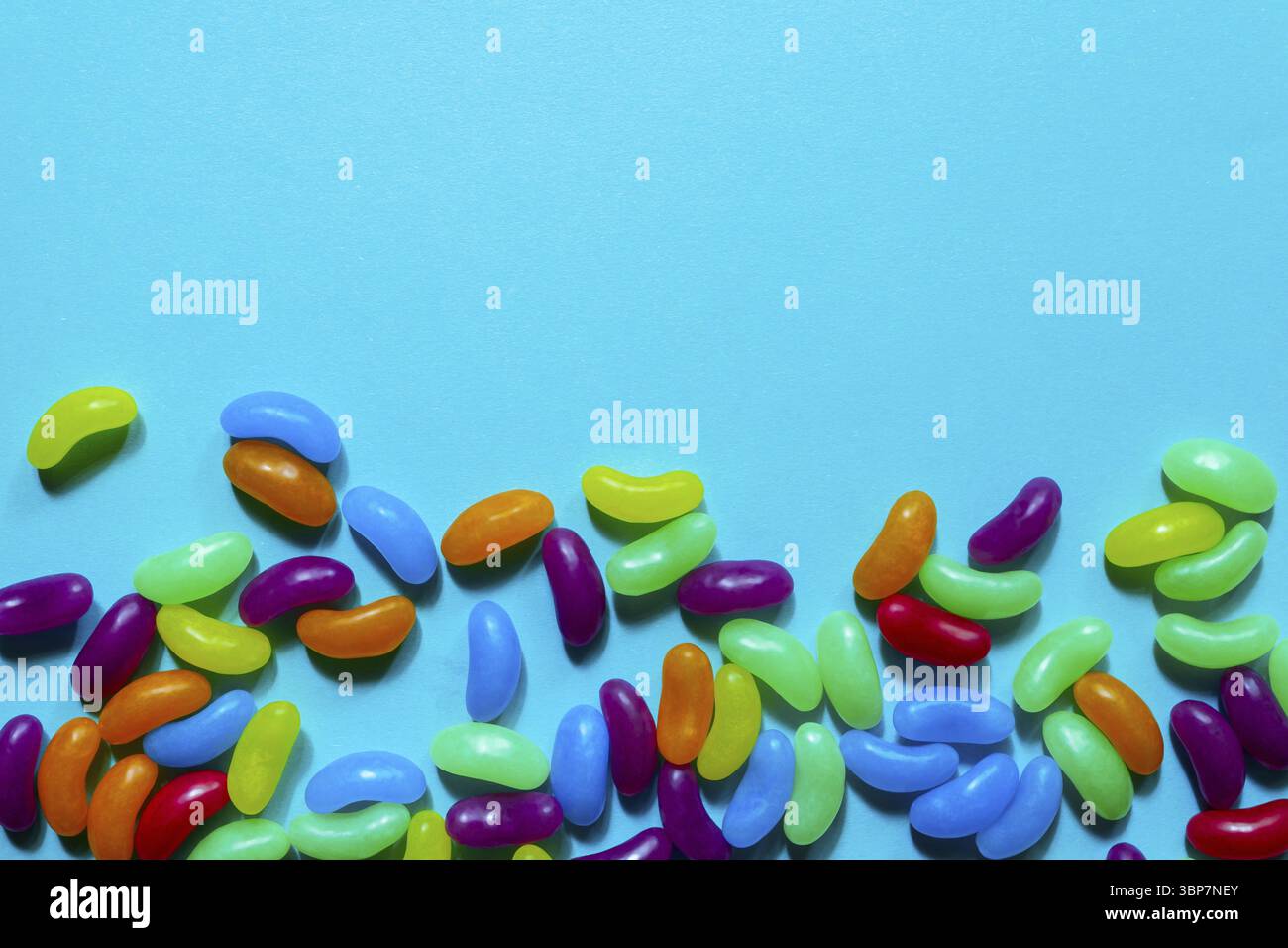 Jelly Beans assortiti bordo con copyspace su sfondo blu Foto Stock