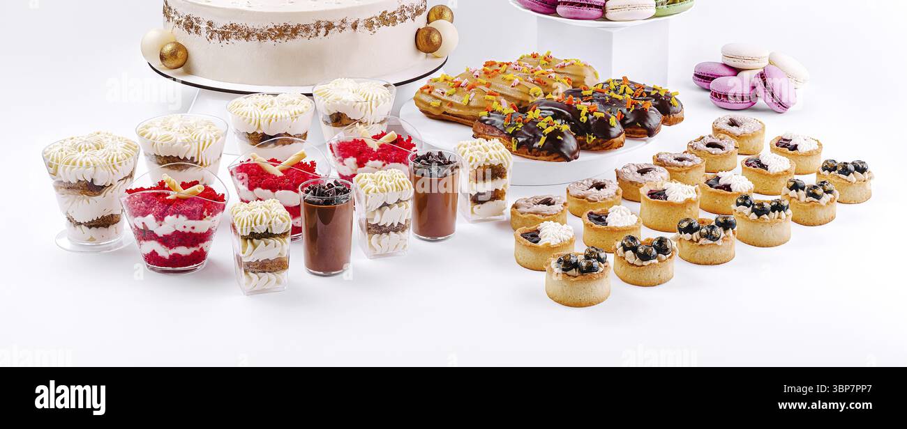 Cibo, Una variopinta gamma di dessert offre varie prelibatezze, tra cui torte, dolci e dessert a strati adornati con panna e frutta, perfetti per Foto Stock