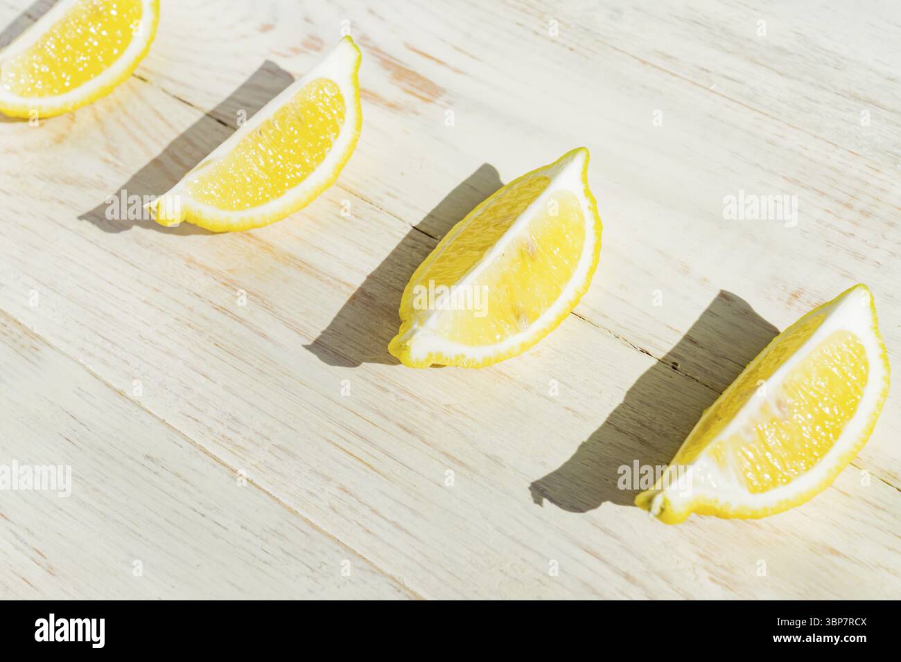 Primo piano di un quarto di limone su un tavolo di legno. Ombre dure in una giornata buia Foto Stock
