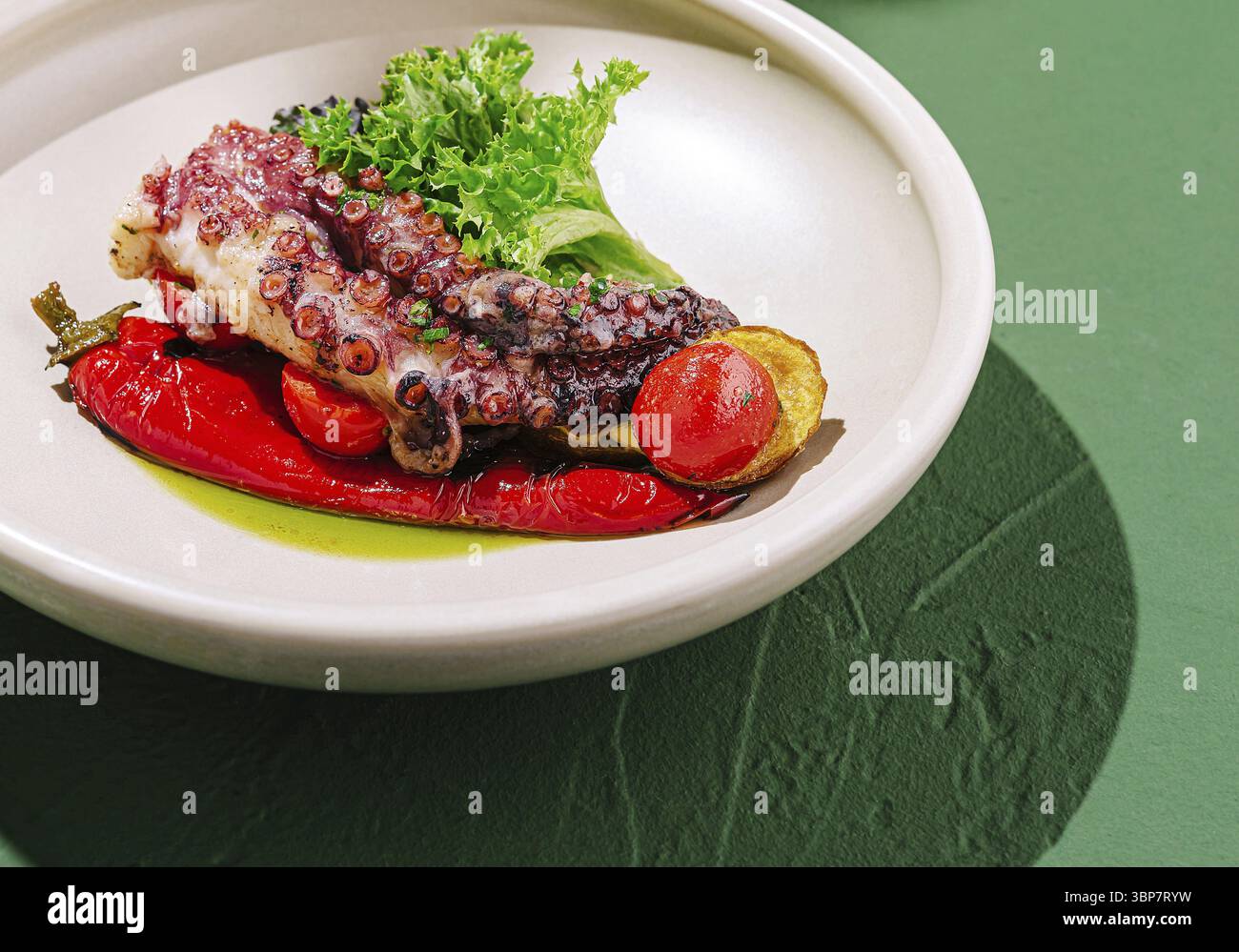 Cibo, Un piatto ben placcato presenta teneri polpi grigliati su peperoni arrostiti e guarniti con verdure fresche. Il pasto è presentato in un ambiente minimalista Foto Stock