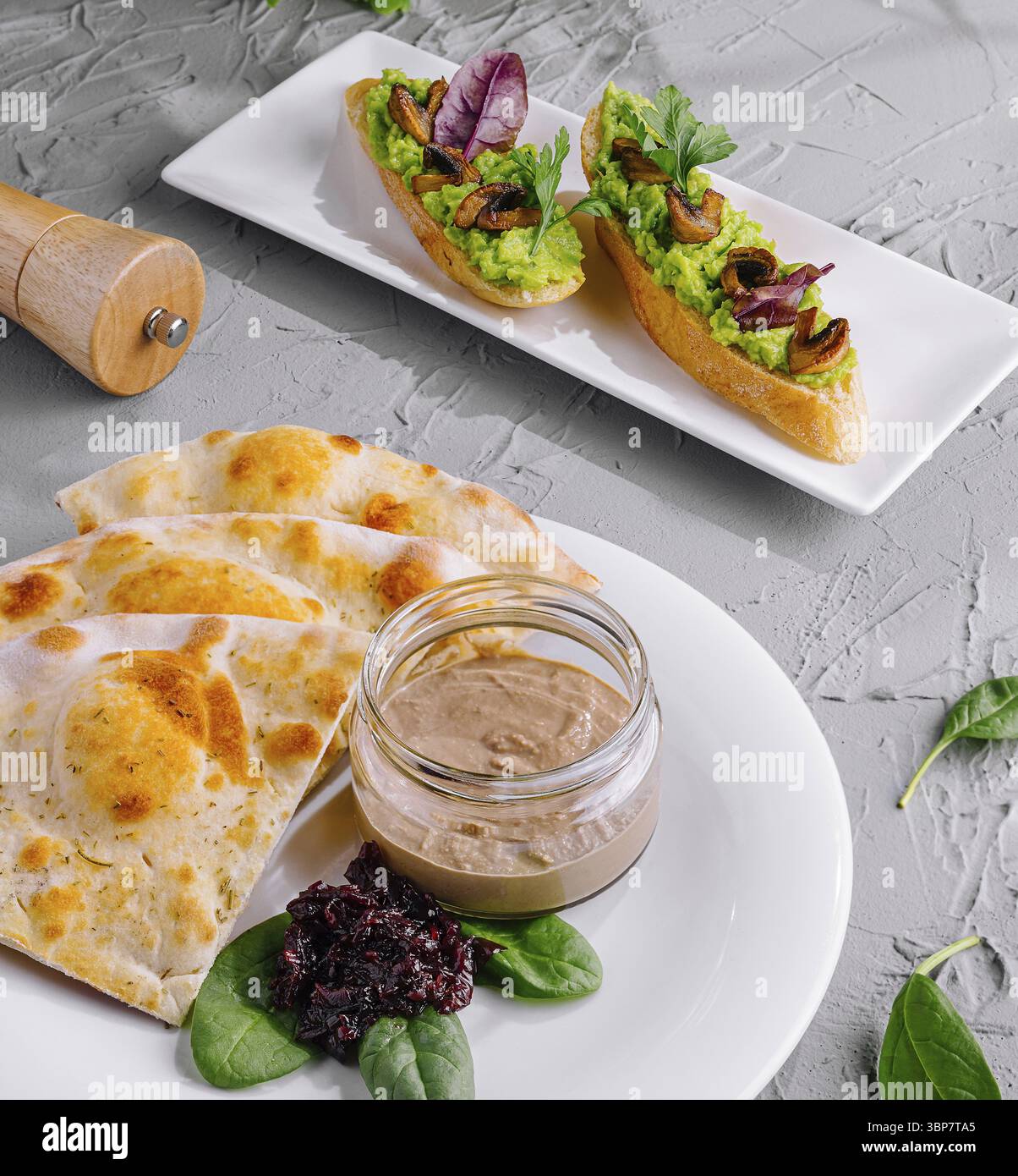 Cibo, bruschette artigianali e soffice pita serviti con salse salate su un moderno piatto di ceramica Foto Stock