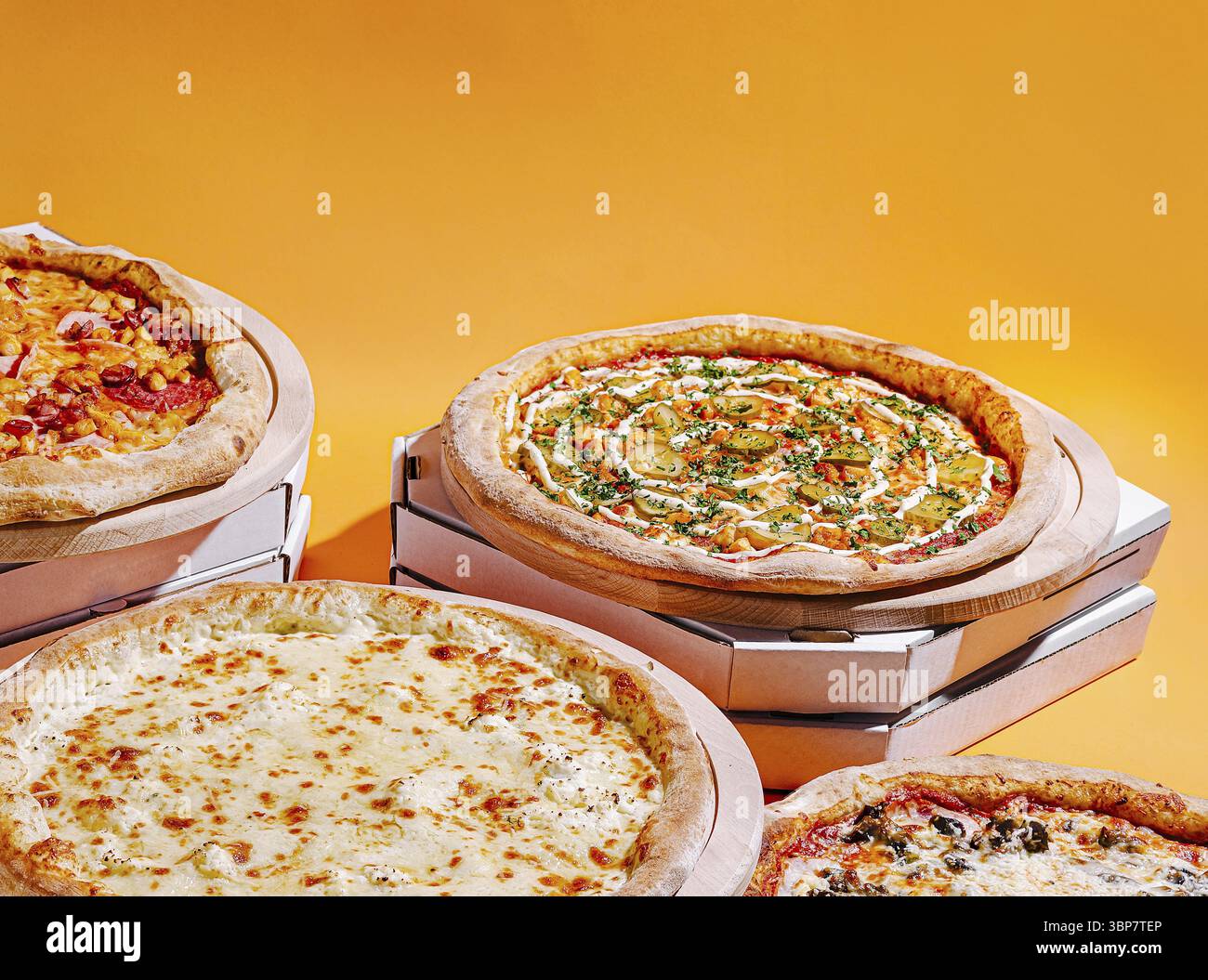 Cibo, quattro deliziose pizze sono esposte su vassoi di cartone, con una varietà di condimenti come formaggio, peperoni ed erbe fresche, tutte agains Foto Stock