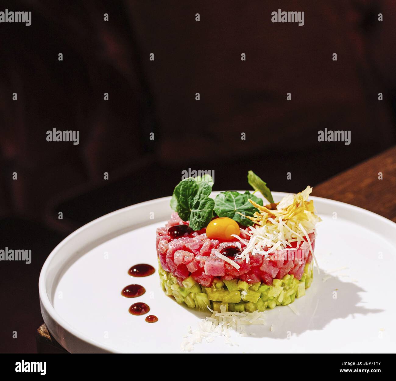 Cibo, Una colorata tartare di sushi è presentata su un piatto bianco in un ambiente raffinato. Il piatto comprende tonno a dadini, avocado e garnisci Foto Stock