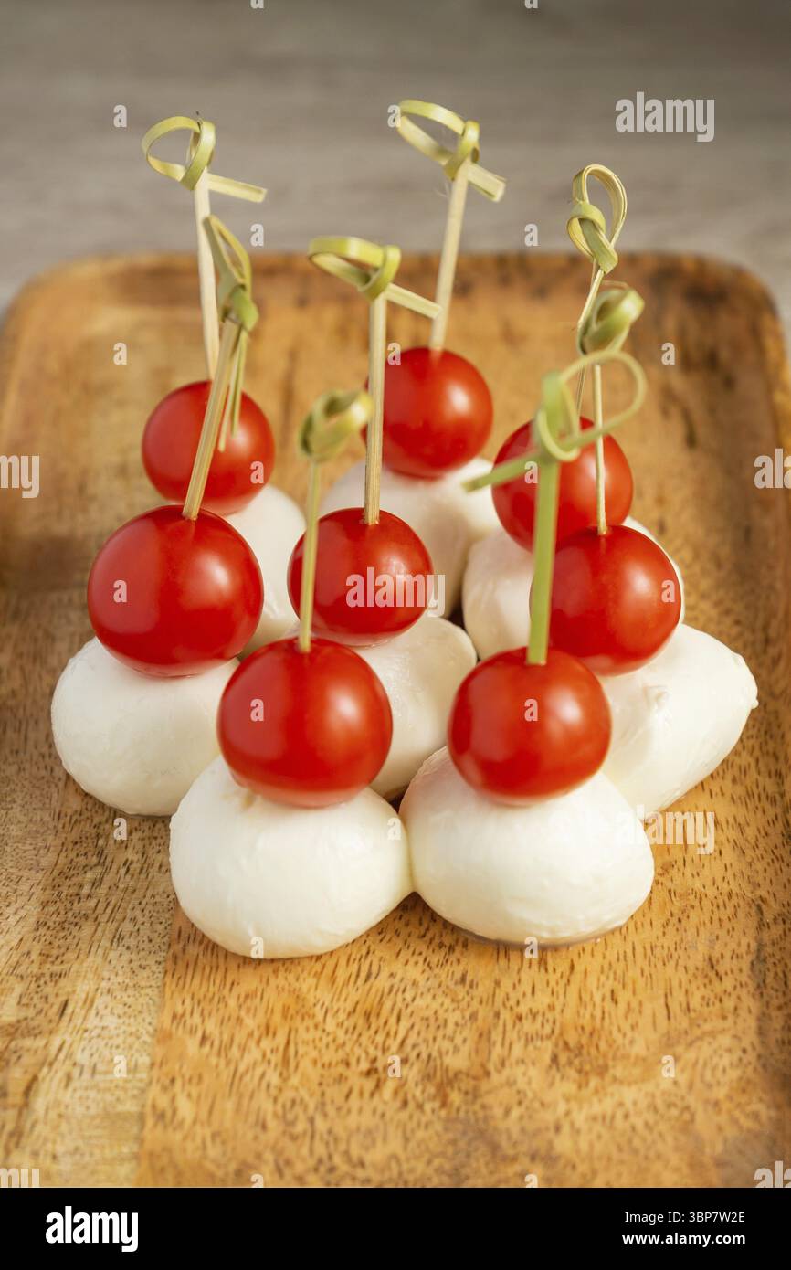 Spuntini e antipasti a buffet. Tartine con mozzarella e pomodori ciliegini serviti su vassoio di legno Foto Stock