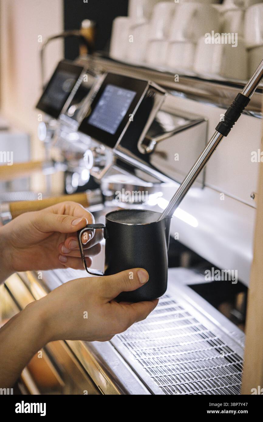 Cibo, barista che prepara la schiuma di latte nella tazza metallica Foto Stock